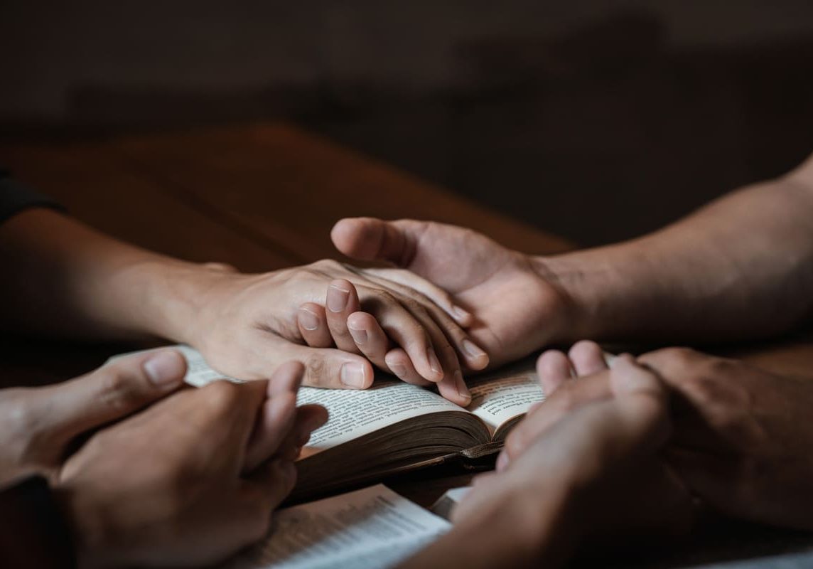 people praying and holding hands